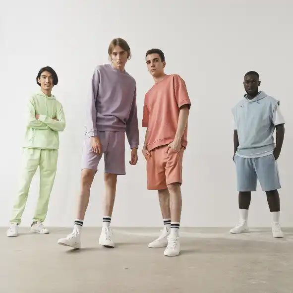 Four people wearing pastel-colored matching sweatsuit sets and white sneakers.